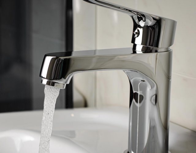 Water flows from the tap or faucet in bathroom. Copy space, close up